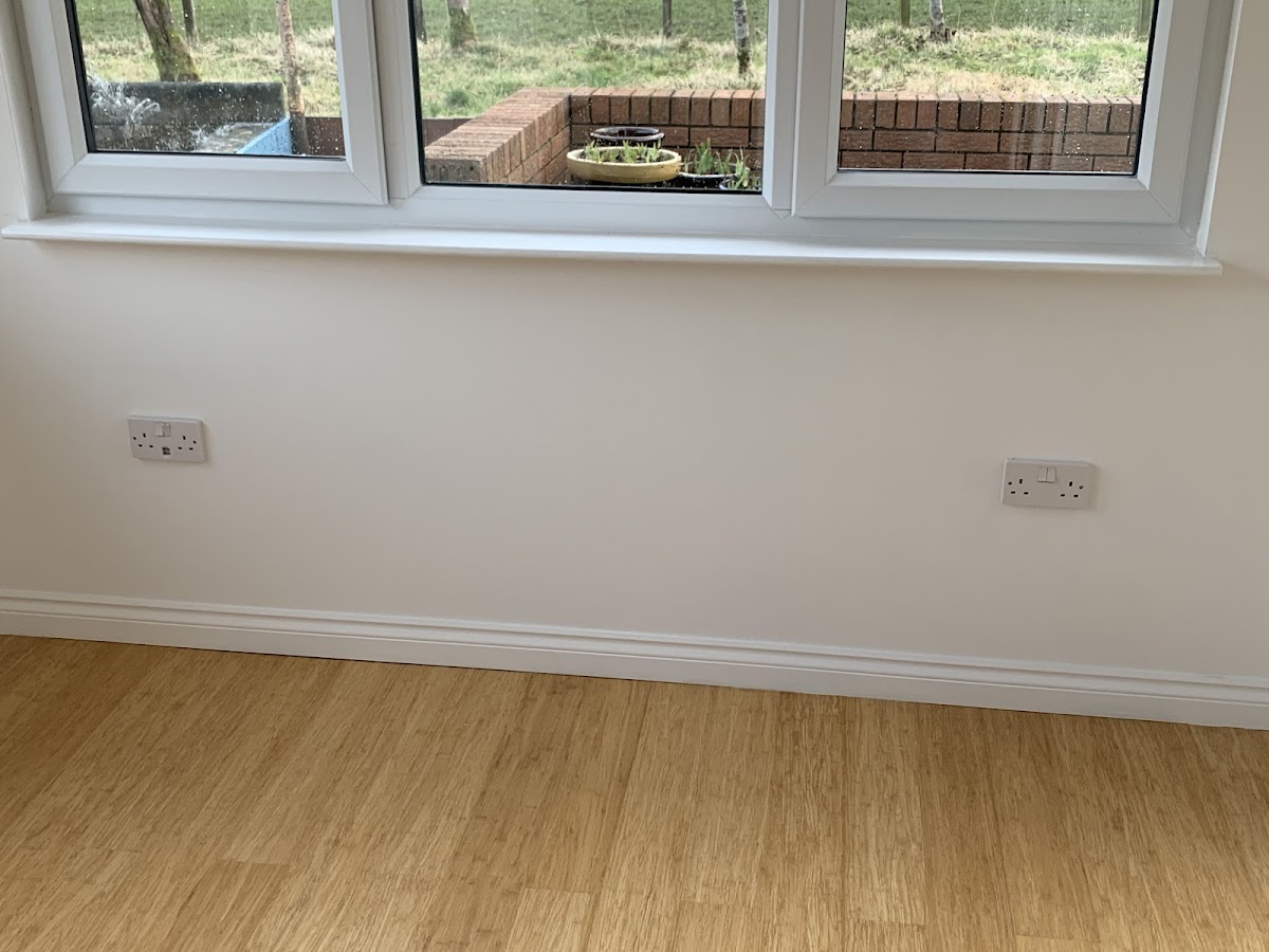New double sockets installed neatly under a window in a fresh-painted room