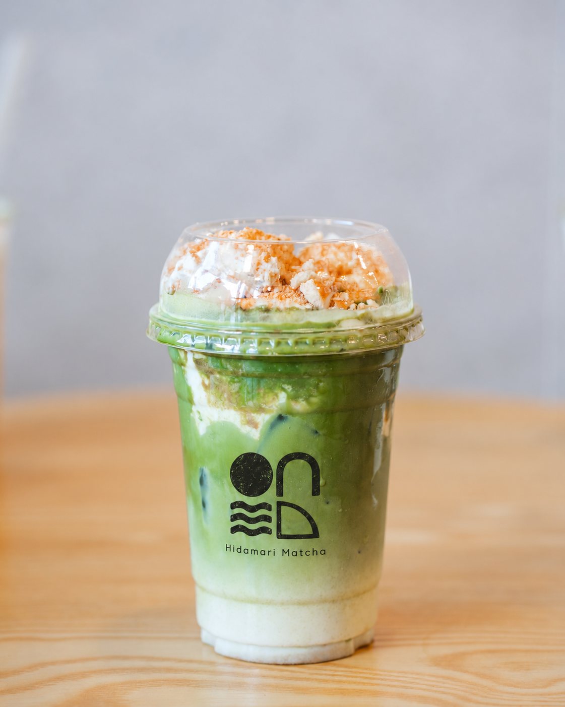 Banana Pudding Matcha Latte, layered green and cream, topped with cream and cookie crumble