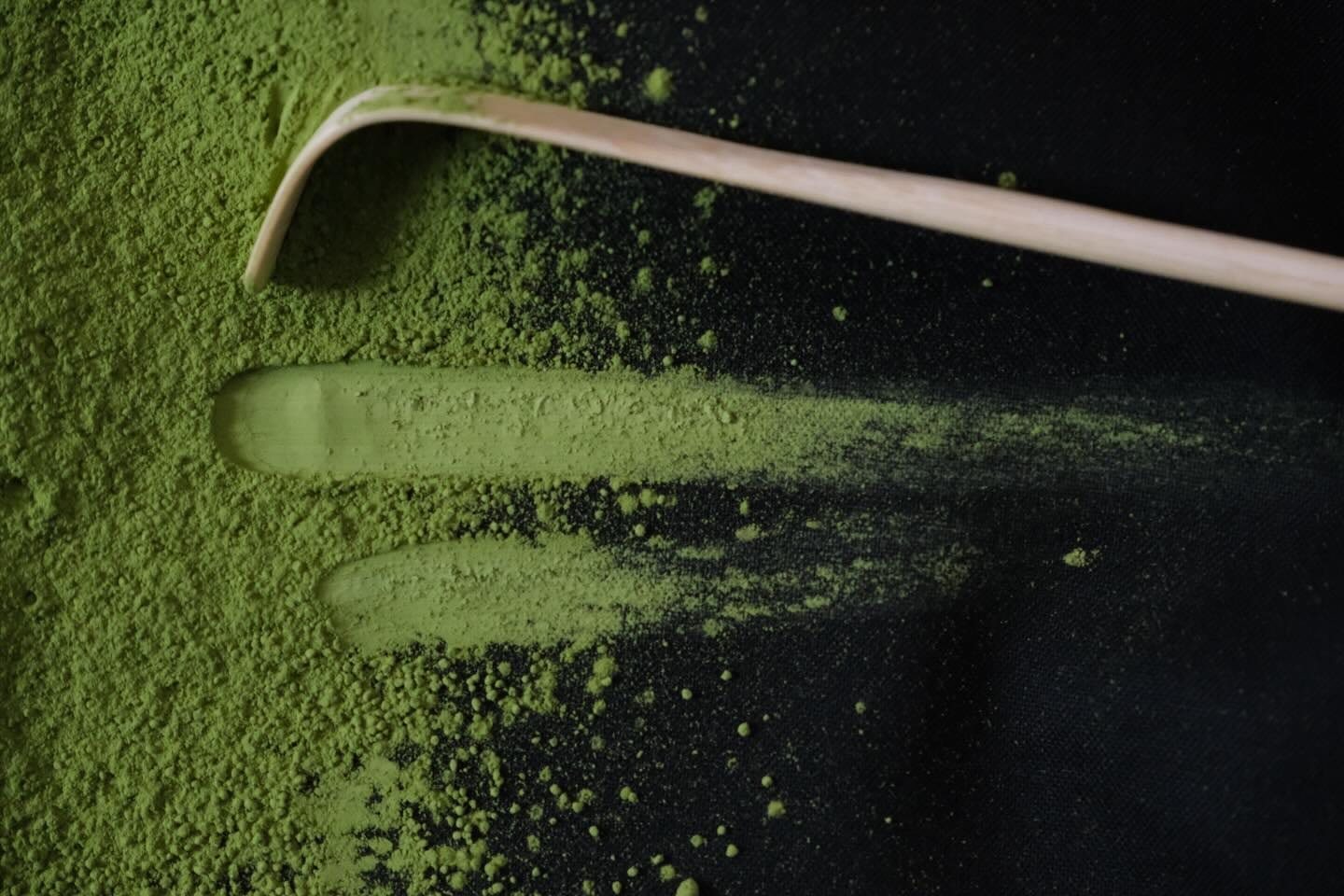 A bamboo tea scoop drawn through fine matcha powder
