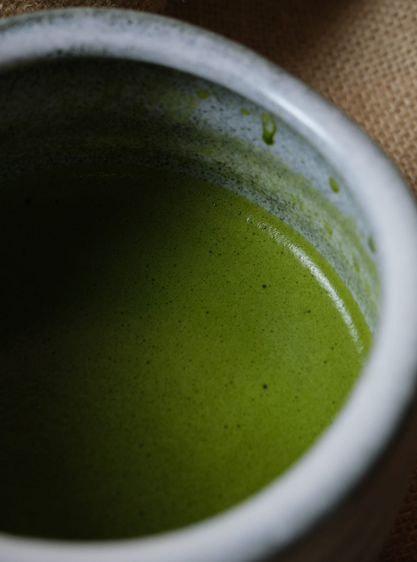 Close-up of whisked matcha in a speckled stoneware bowl