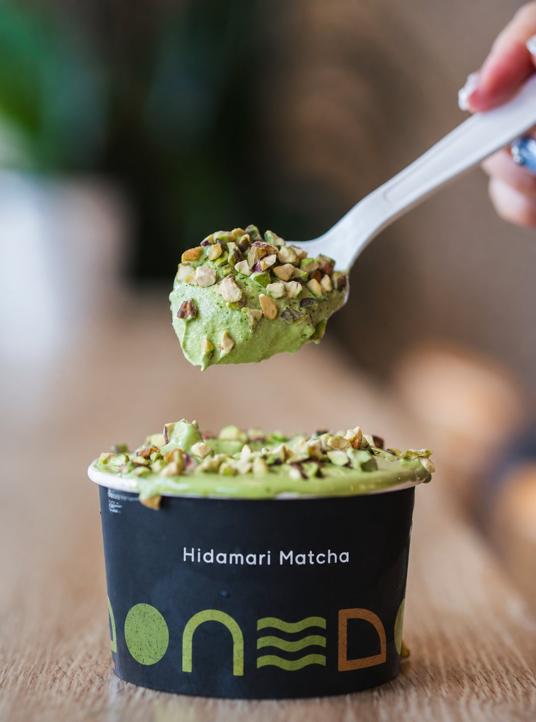 A spoon lifting Matcha Pistachio Gelato from a black Hidamari Matcha cup