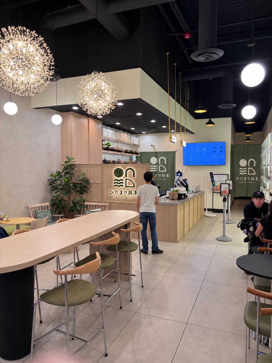 Inside the café: a long oak table, olive chairs and dandelion pendant lights